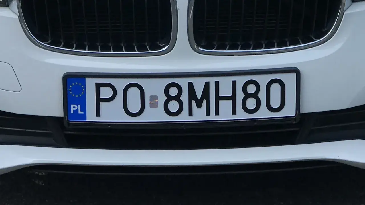 Tablice rejestracyjne sprawdzanie: polskie PO-8MH80 na białym samochodzie.