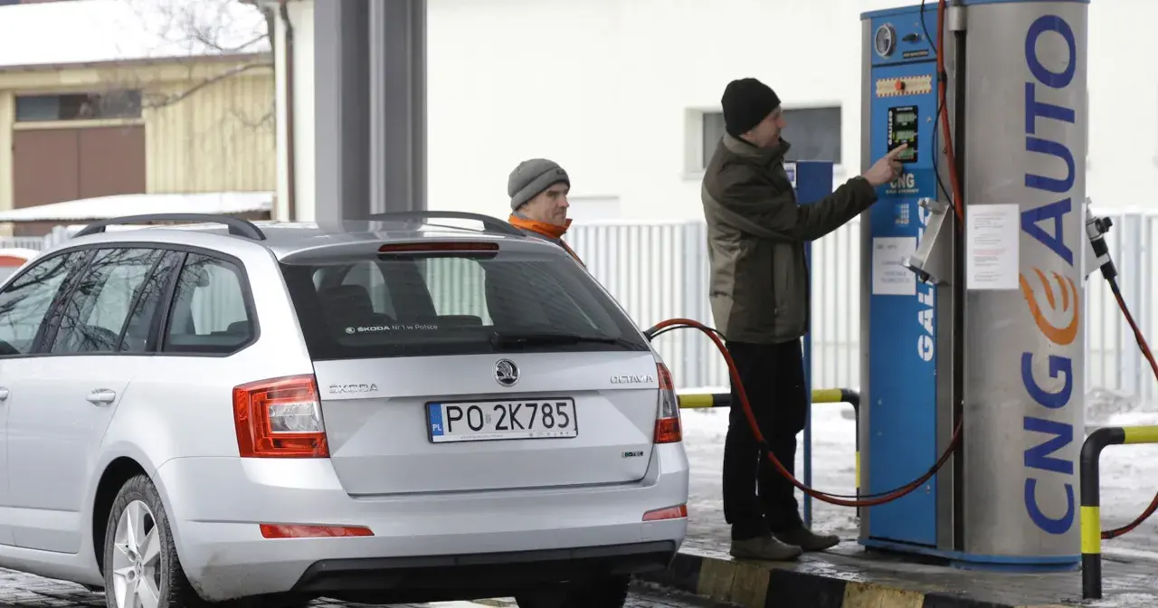 Srebrny samochód Skoda z podłączoną dyszą do tankowania gazu CNG na stacji.
