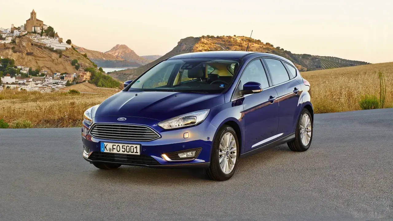 Niebieski Ford Focus MK3 1.6 TDCI na tle malowniczej hiszpańskiej wioski i gór.