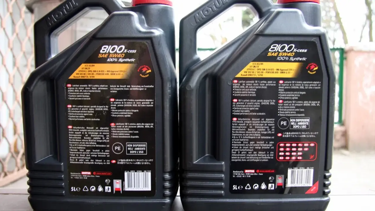 Dwie kanistry oleju silnikowego Motul 8100 X-cess SAE 5W40, jeden oznaczony jako "FAKE", drugi jako "ORI".