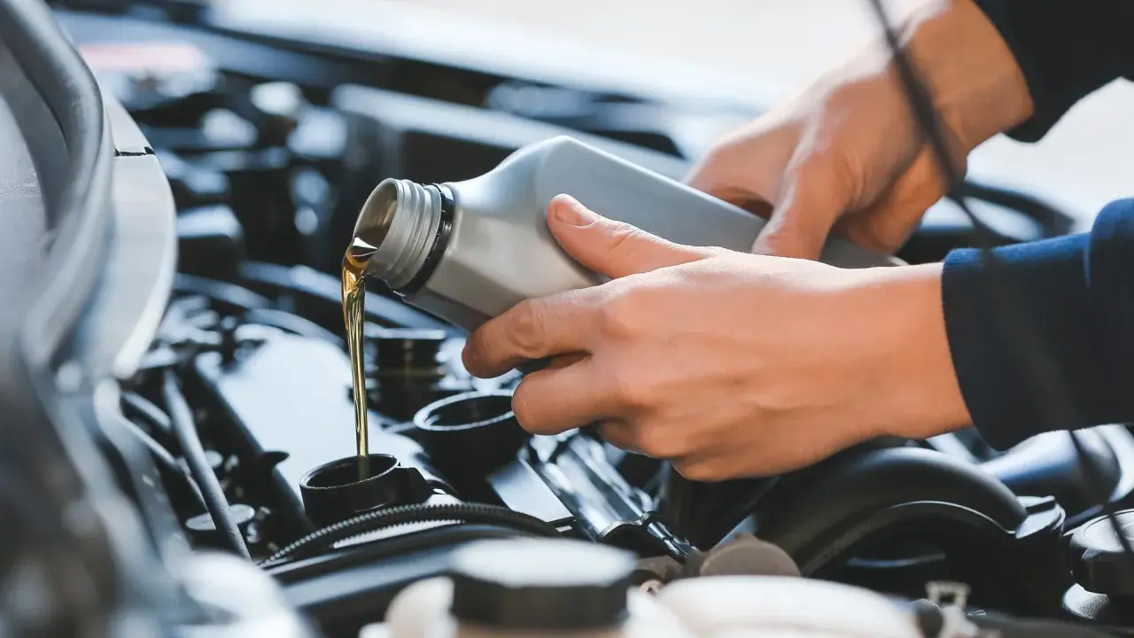 Ręce wlewające olej silnikowy do silnika samochodu.