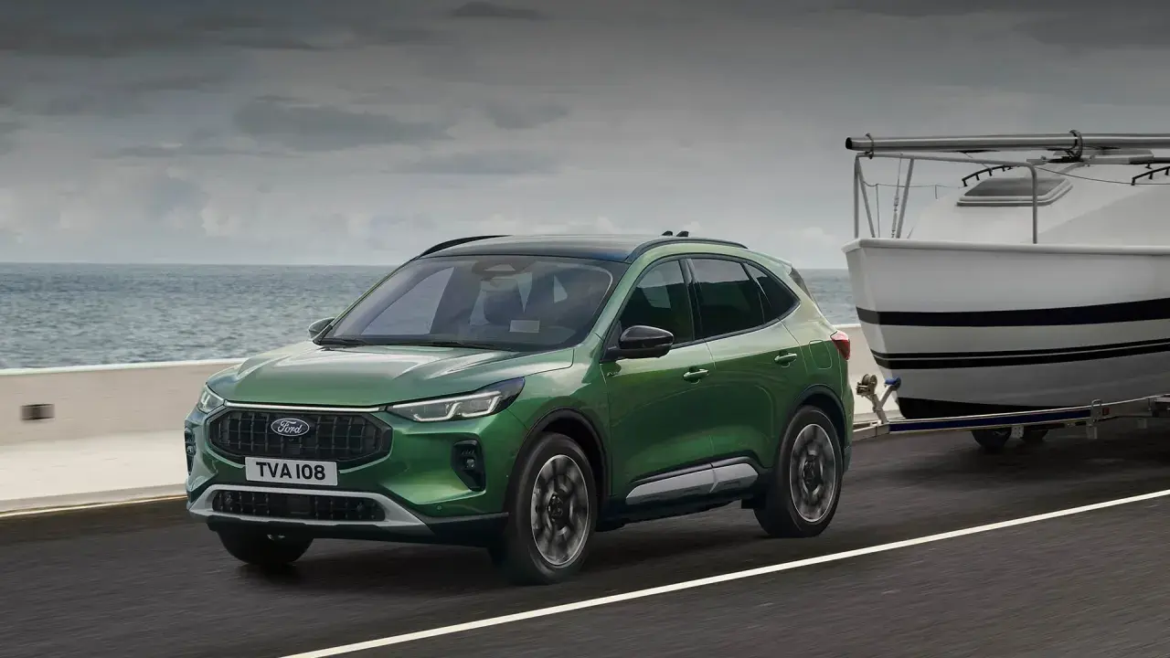 Zielony Ford Kuga z przyczepą i łodzią, idealny na wakacyjne wyjazdy. Sprawdź ford kuga cena!