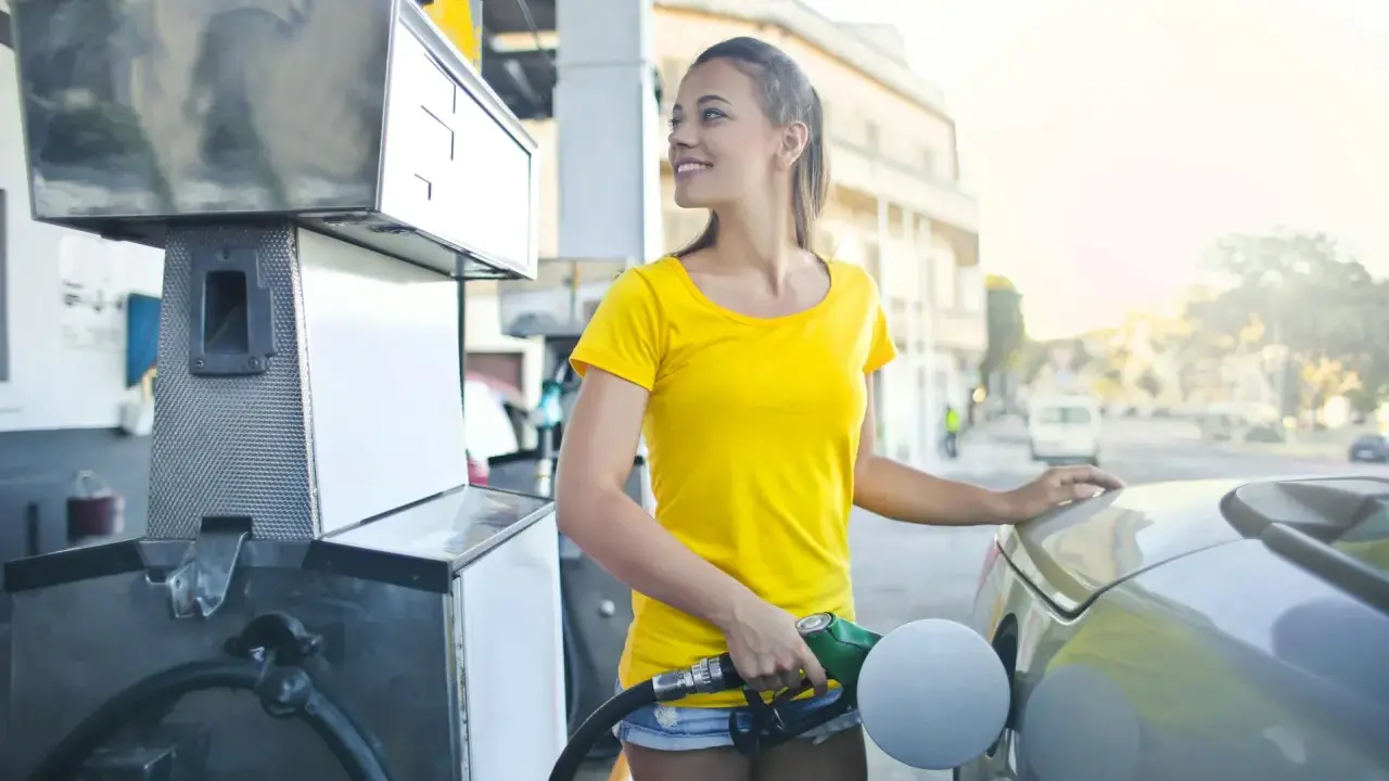 Uśmiechnięta dziewczyna tankuje auto, nalewając Vervę 98.
