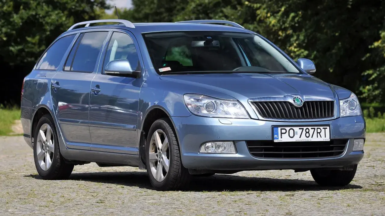 Niebieska Skoda Octavia 2010 kombi stoi na brukowanym podjeździe, otoczona zielenią.