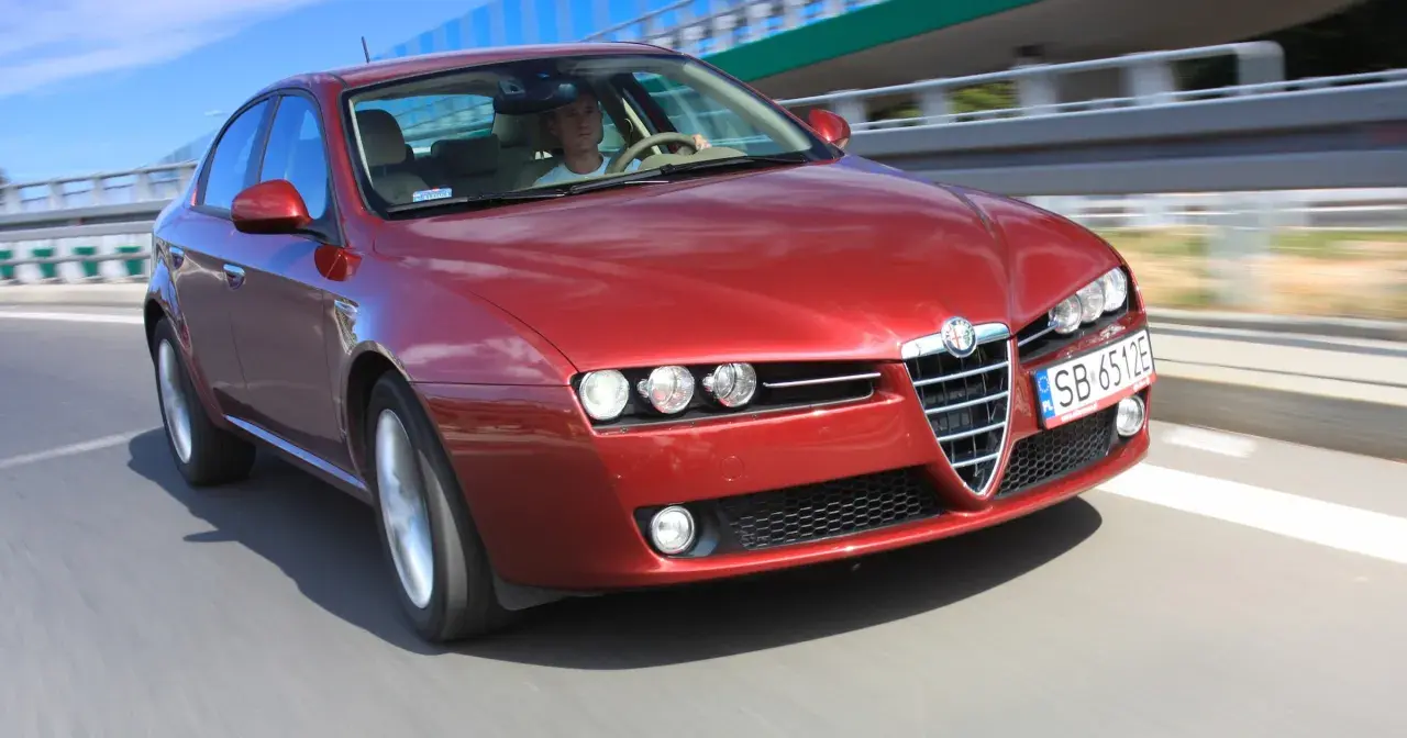 Czerwone Alfa Romeo 159 1.9 JTD pędzi po autostradzie.