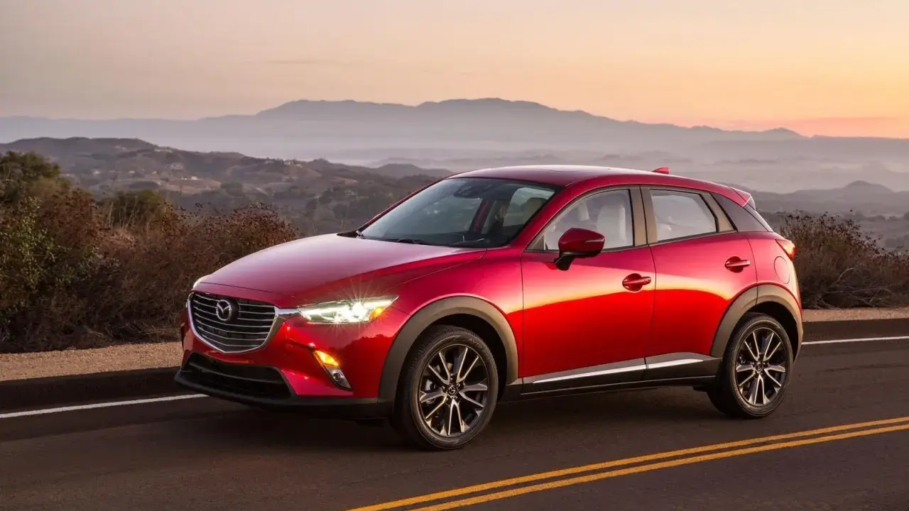 Czerwona Mazda CX-3 na tle górskiego krajobrazu o zachodzie słońca. Elegancka linia nadwozia i lśniący lakier.