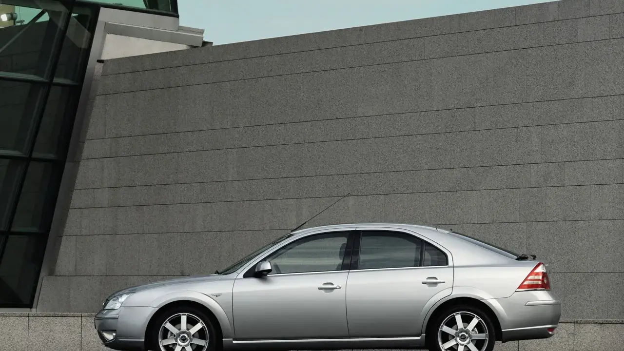 Srebrny Ford Mondeo MK3 2.0 TDCI stoi przed nowoczesnym budynkiem z kamienną fasadą.