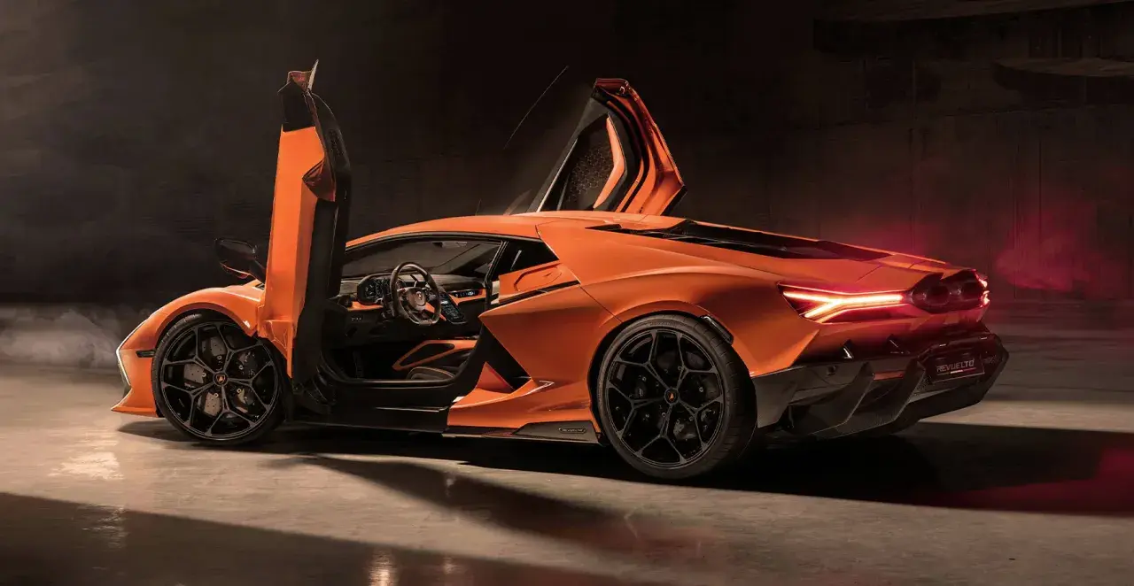 Pomarańczowy Lamborghini Revuelto z otwartymi drzwiami typu nożycowego, prezentujący sportowe wnętrze i agresywną sylwetkę.