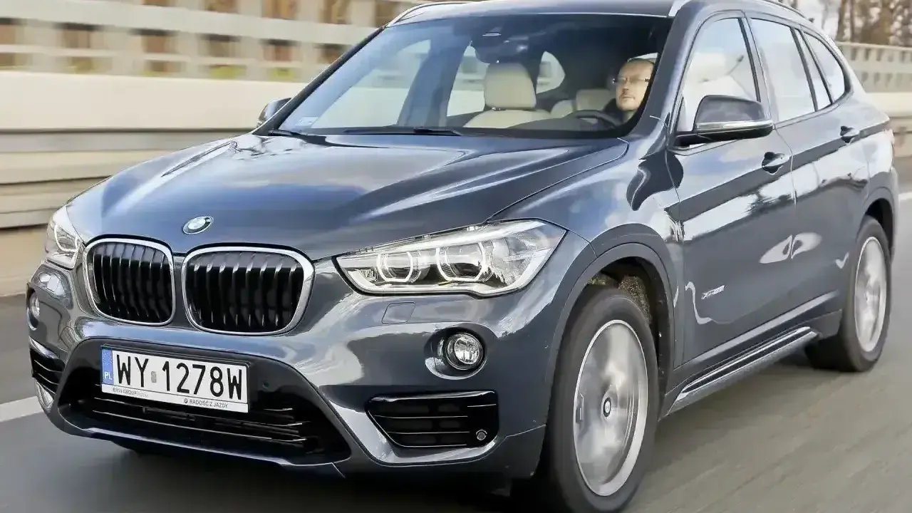 Ciemnoszary BMW X1 2025 z kierowcą za kierownicą, jadący po drodze.