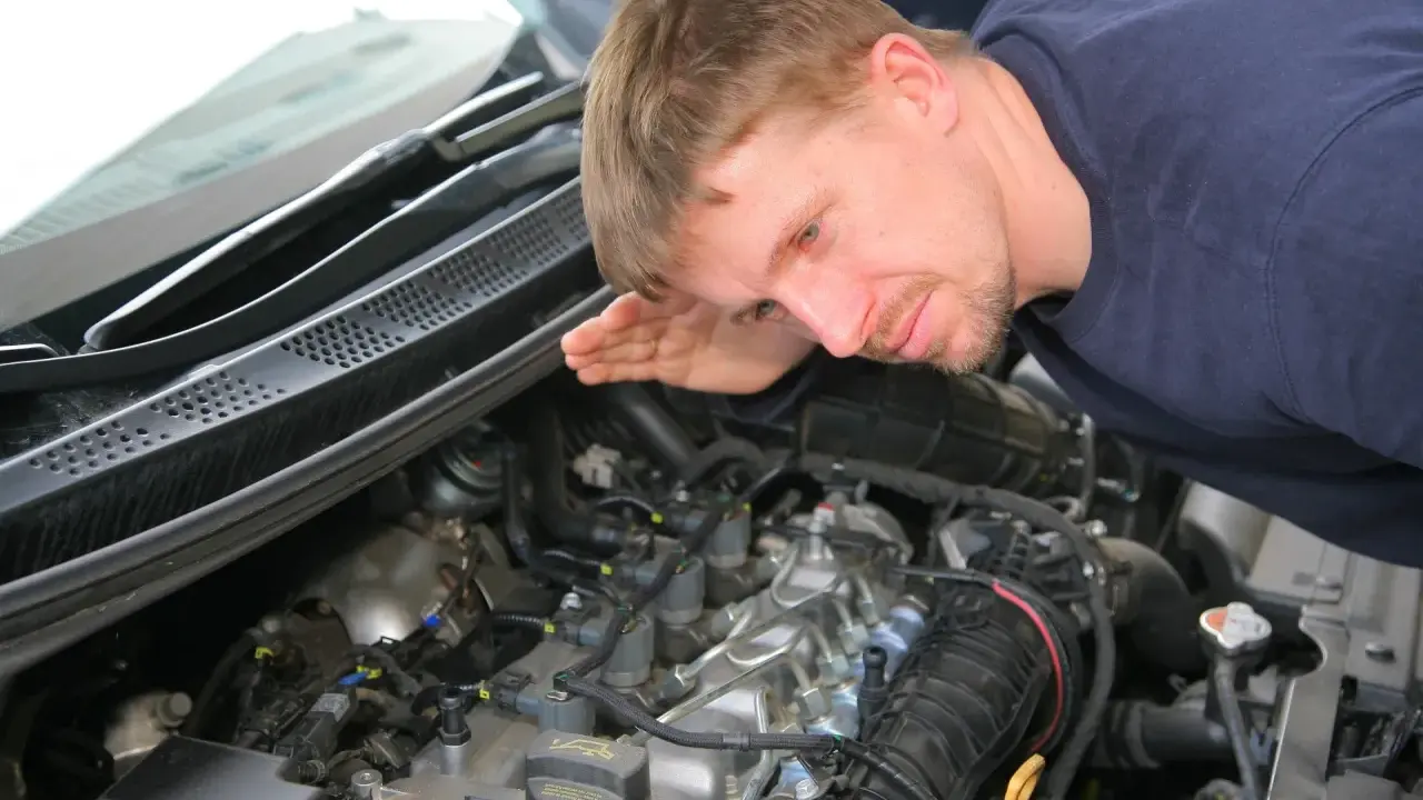 Mechanik nasłuchuje silnika, szukając oznak nieszczelnej odmy.