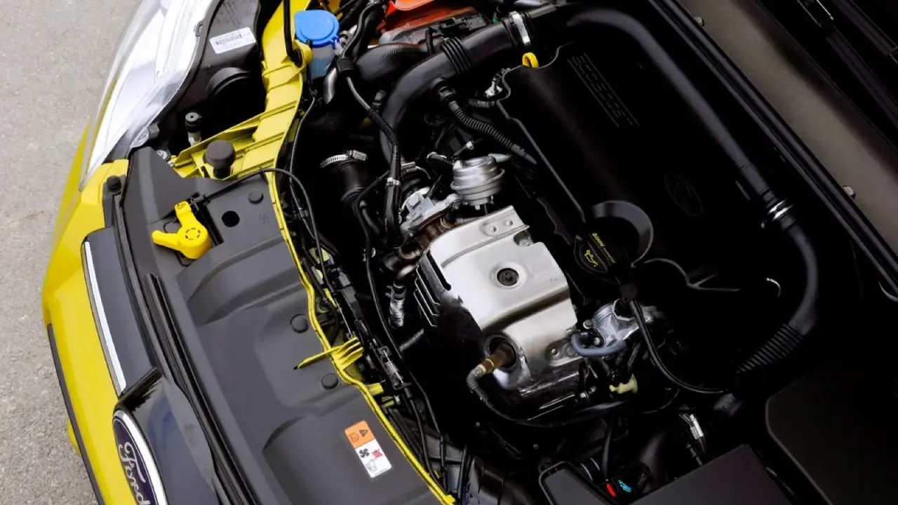 Silnik 1.0 Ecoboost w żółtym Fordzie. Widoczne elementy układu dolotowego, turbosprężarki i osłony silnika.