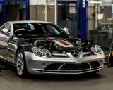Srebrny Mercedes McLaren z otwartą maską, odsłaniającą potężny silnik, stoi w warsztacie.
