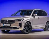 Eleganckie, nowe Volvo w kolorze szampańskim prezentuje się imponująco na tle niebieskiego tła.