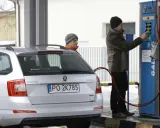Srebrny samochód Skoda z podłączoną dyszą do tankowania gazu CNG na stacji.