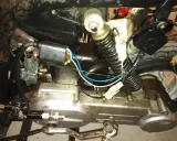 Silnik motoroweru z widocznym iskrownikiem, gaźnikiem i świecą zapłonową.