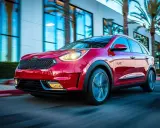 Czerwony Kia Niro w ruchu, z widocznymi światłami i felgami. Choć auto wygląda dynamicznie, warto rozważyć jego wady przed zakupem.
