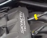 Silnik SKYACTIV TECHNOLOGY, jeden z najlepszych silników benzynowych, z widocznymi przewodami i złączkami.