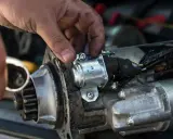 Mechanik naprawia rozrusznik w aucie, przykręcając element.