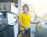 Uśmiechnięta dziewczyna tankuje auto, nalewając Vervę 98.