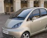 Złoty Tata Nano na brukowanym placu przed zabytkową kamienicą.