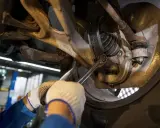 Mechanik dokręca śrubę w zawieszeniu samochodu kluczem.