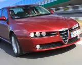 Czerwone Alfa Romeo 159 1.9 JTD pędzi po autostradzie.