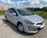 Srebrny Hyundai i30 1.4 benzyna zaparkowany na kostce brukowej, w tle zielona trawa i budynki.