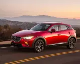 Czerwona Mazda CX-3 na tle górskiego krajobrazu o zachodzie słońca. Elegancka linia nadwozia i lśniący lakier.