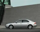 Srebrny Ford Mondeo MK3 2.0 TDCI stoi przed nowoczesnym budynkiem z kamienną fasadą.