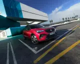 Czerwony Seat Arona, jeden z najnowszych seat modele, zaparkowany przy nowoczesnym budynku z niebieskimi akcentami.
