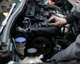 Mechanik pracuje przy silniku benzynowym, jego ręce są ubrudzone smarem.
