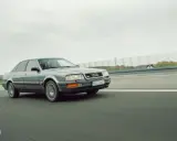 Szary Audi V8 pędzi po autostradzie, chmury na niebie i zielone drzewa w tle.