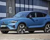 Niebieskie Volvo C40 Recharge, elektryczny SUV, parkuje przed budynkiem z numerem 02.
