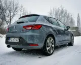 Szary Seat Leon FR w zimowej scenerii, pokryty śniegiem.