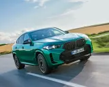 Zielony BMW X6 M Competition, jakby wyłaniał się z krajobrazu, niczym **formentor** w drodze na szczyt.