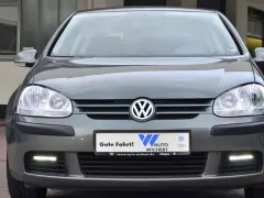 Szare auto z włączonymi światłami do jazdy dziennej.