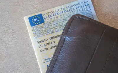 Dowód rejestracyjny pojazdu z PL i adresem Starostwa Czarnkowskiego, schowany w brązowym etui. Po rejestracja dokument gotowy do drogi.