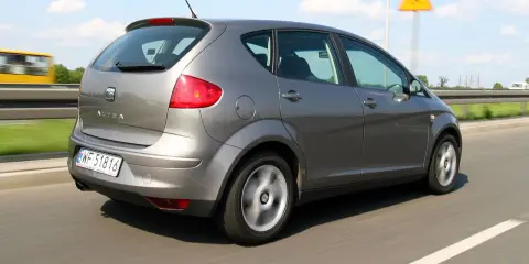 Szary Seat Altea XL jedzie autostradą. W tle widać żółty autobus i znak ostrzegawczy.