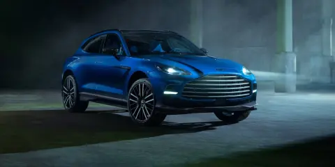 Niebieski Aston Martin DBX 707 lśni w mrocznym, industrialnym otoczeniu.