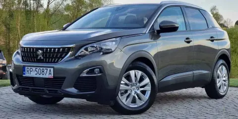 Szary Peugeot 3008 używany z salonu, z polskimi tablicami RP 5087A, zaparkowany na kostce brukowej.