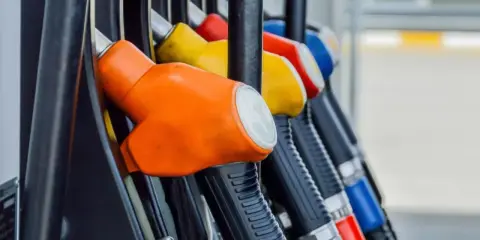 Kolorowe pistolety na stacji paliw, gotowe do tankowania. Jeden z nich, pomarańczowy, sugeruje, że można nim nalać verva diesel.