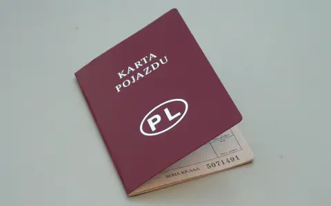 Czerwona karta pojazdu z białym napisem "PL" i numerem seryjnym. Dokument jest otwarty, ukazując dane pojazdu.