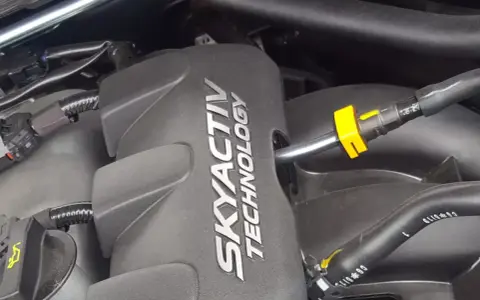 Silnik SKYACTIV TECHNOLOGY, jeden z najlepszych silników benzynowych, z widocznymi przewodami i złączkami.