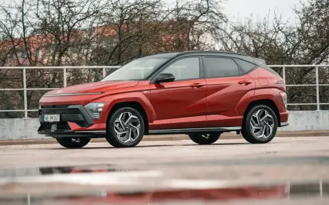 Nowy Hyundai Kona Hybrid w kolorze ognistej czerwieni, z czarnym dachem, prezentuje się dynamicznie na tle zimy.