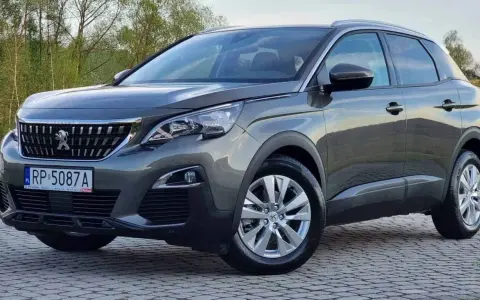 Szary Peugeot 3008 używany z salonu, z polskimi tablicami RP 5087A, zaparkowany na kostce brukowej.