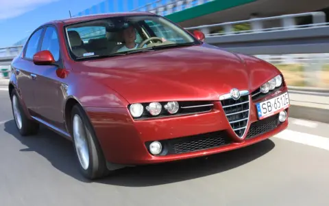 Czerwone Alfa Romeo 159 1.9 JTD pędzi po autostradzie.