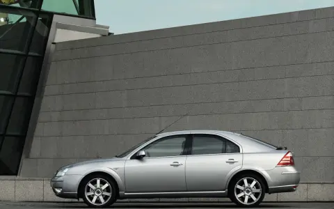 Srebrny Ford Mondeo MK3 2.0 TDCI stoi przed nowoczesnym budynkiem z kamienną fasadą.