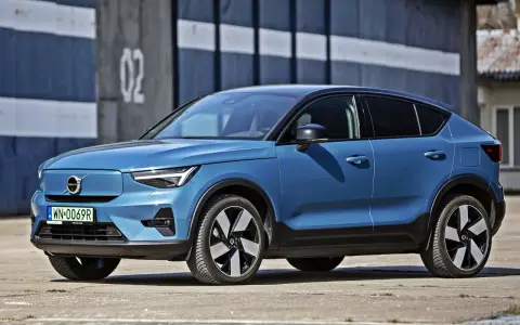 Niebieskie Volvo C40 Recharge, elektryczny SUV, parkuje przed budynkiem z numerem 02.