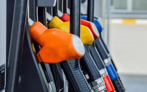 Kolorowe pistolety na stacji paliw, gotowe do tankowania. Jeden z nich, pomarańczowy, sugeruje, że można nim nalać verva diesel.