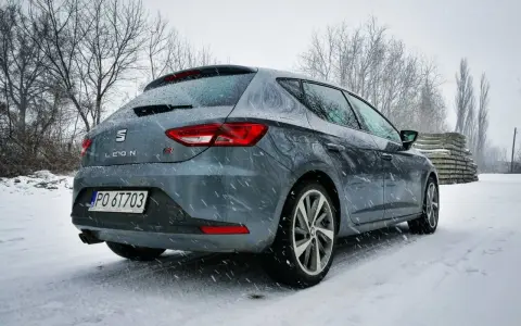 Szary Seat Leon FR w zimowej scenerii, pokryty śniegiem.